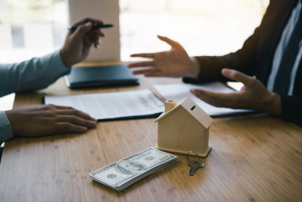 Business people home sales broker is using a pen pointing to the house model and describing the various components of the house.